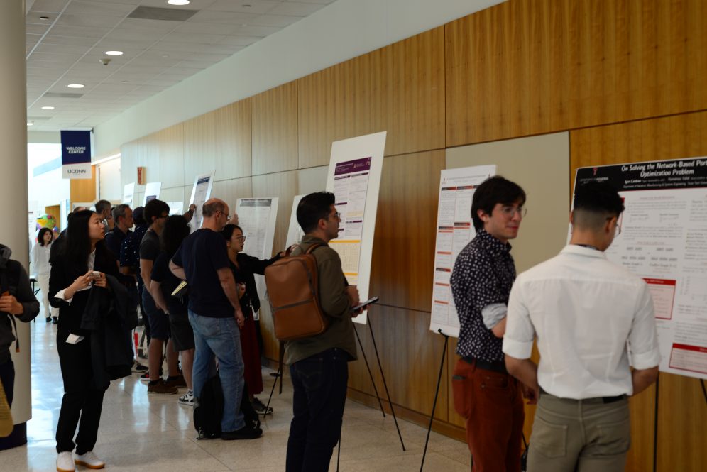 A crowd of people look at research posters.