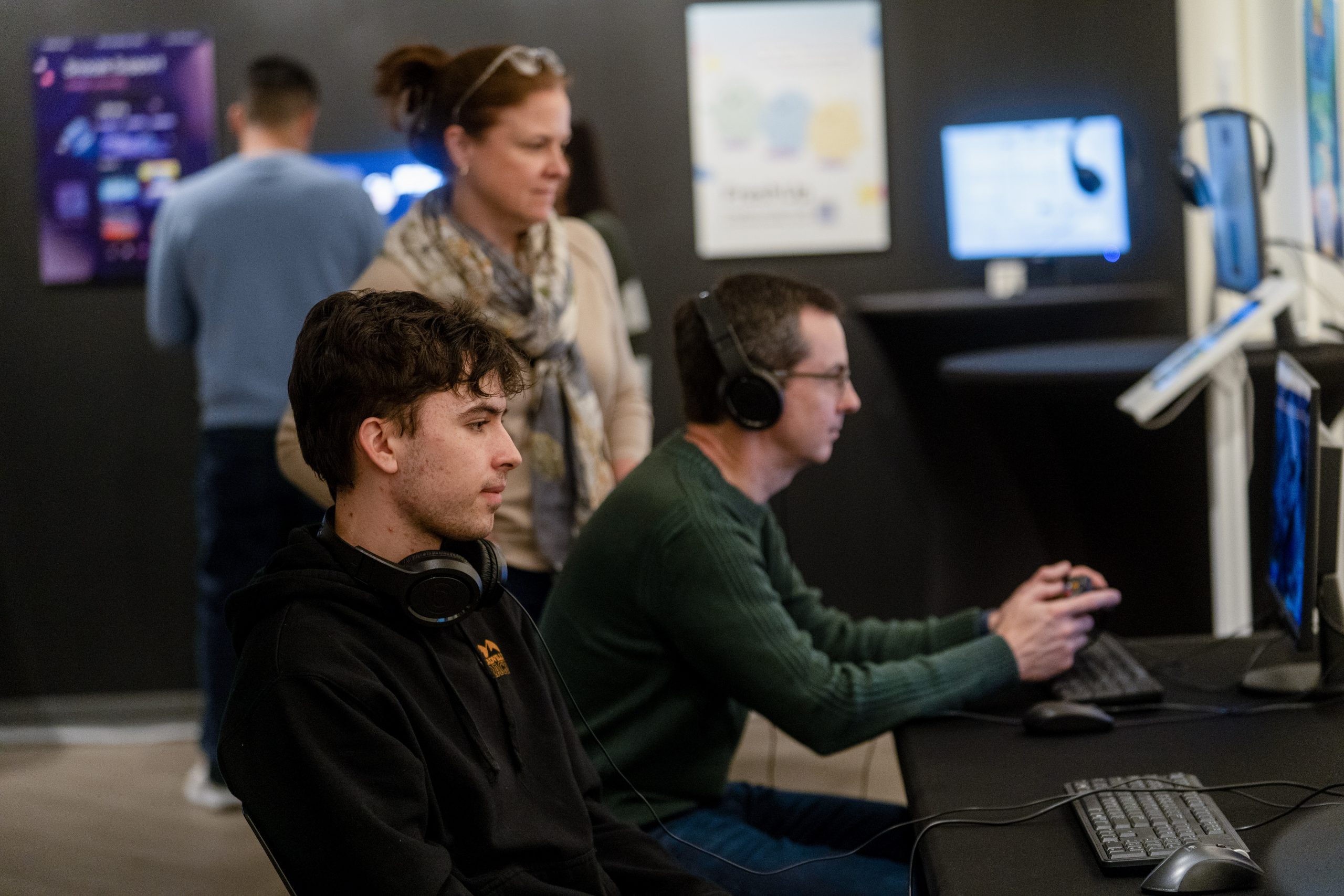 Two men sit at desktop computers playing video games.