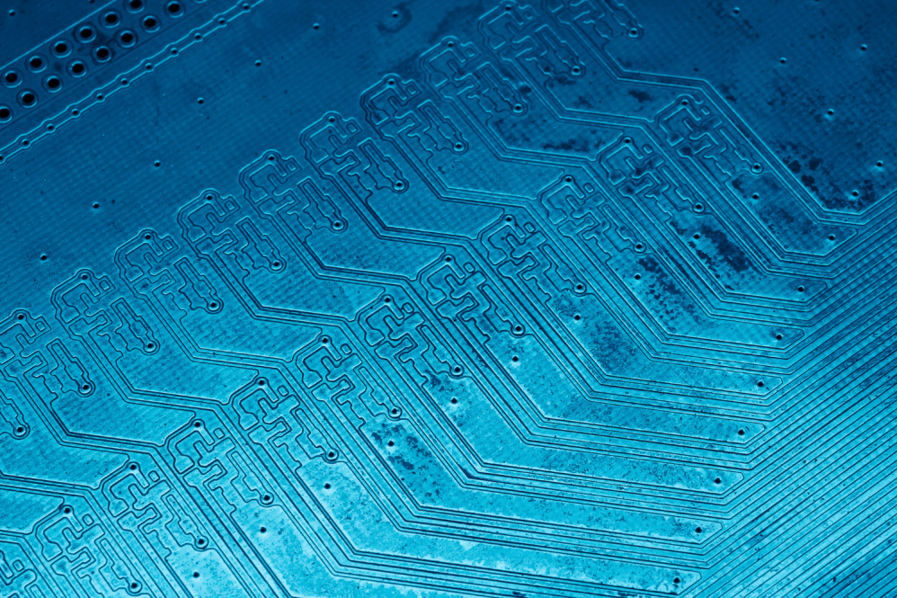 Close-up image of a blue printed circuit board with intricate conductive pathways.