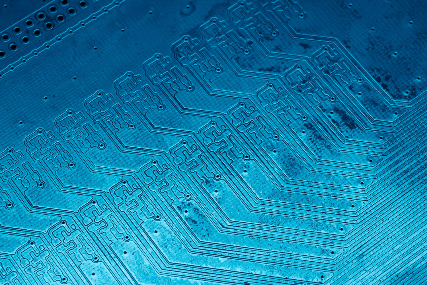 Close-up image of a blue printed circuit board with intricate conductive pathways.