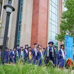 Graduates process outside.