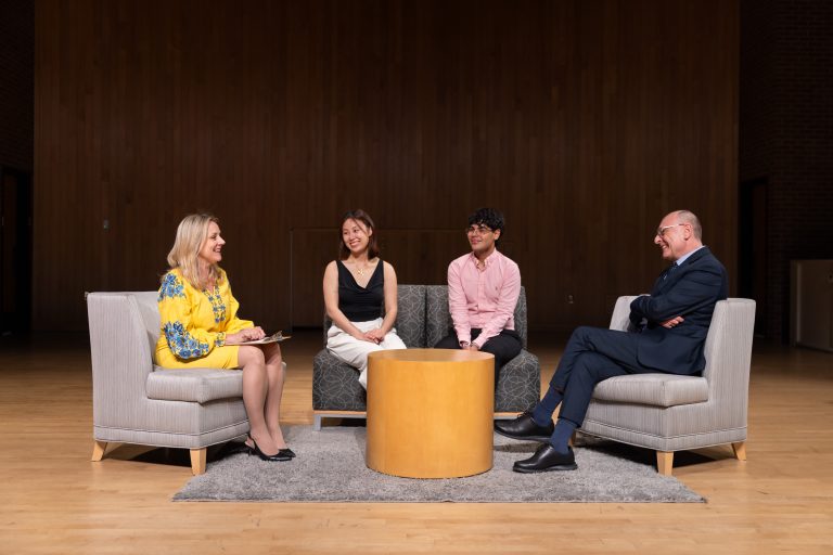 Four people sitting around a table on stage talking