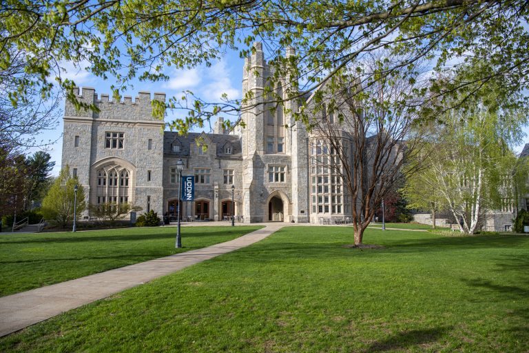 A scenic photo of a building with green grass and leaves on trees