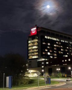 exterior shot of UConn John Dempsey Hospital at night with building sign lit red