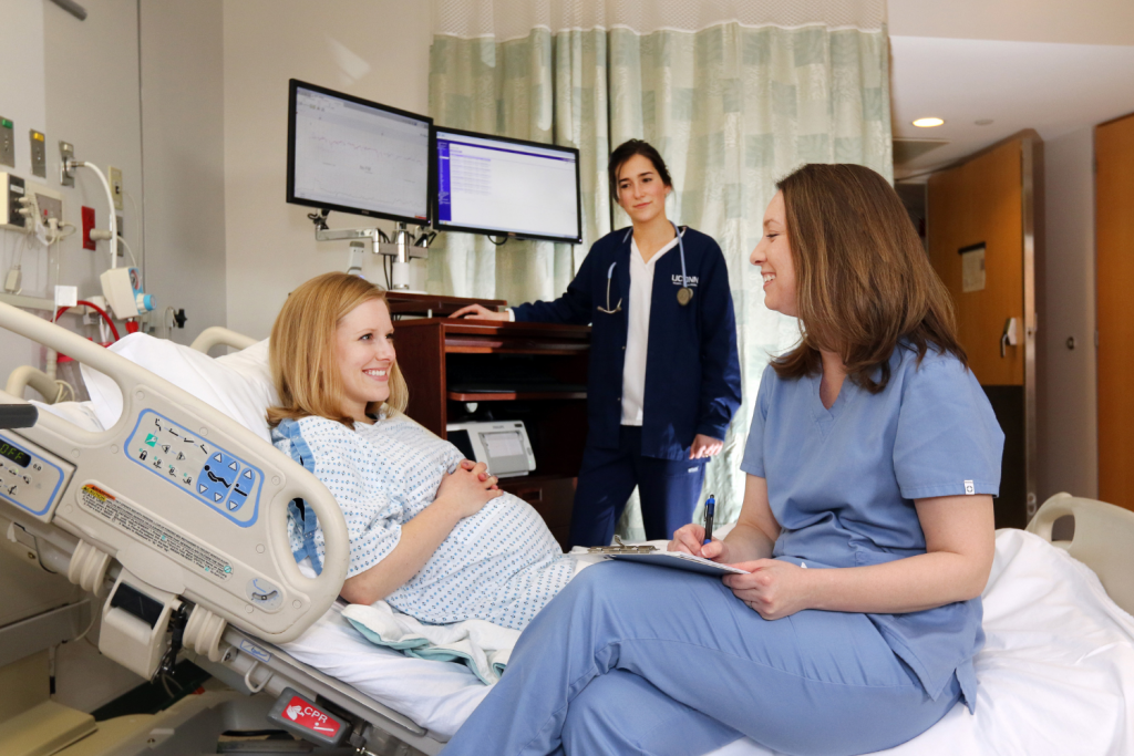 two nurses around the bed of a pregnant woman