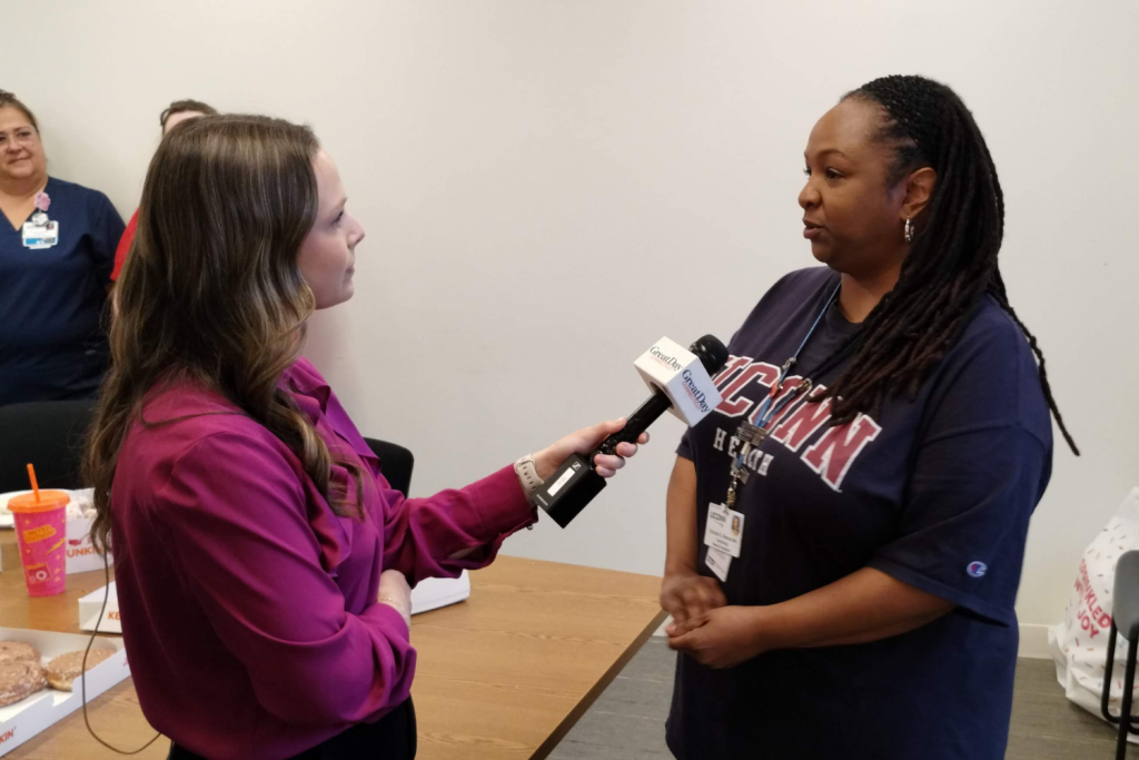 A white woman holds a microphone up to a black woman