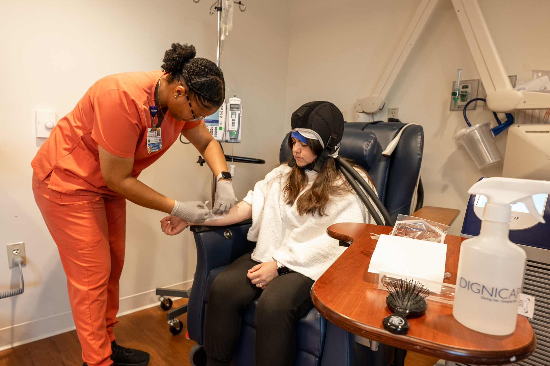 A woman in a cap sitting in a chair being treated by a nurse