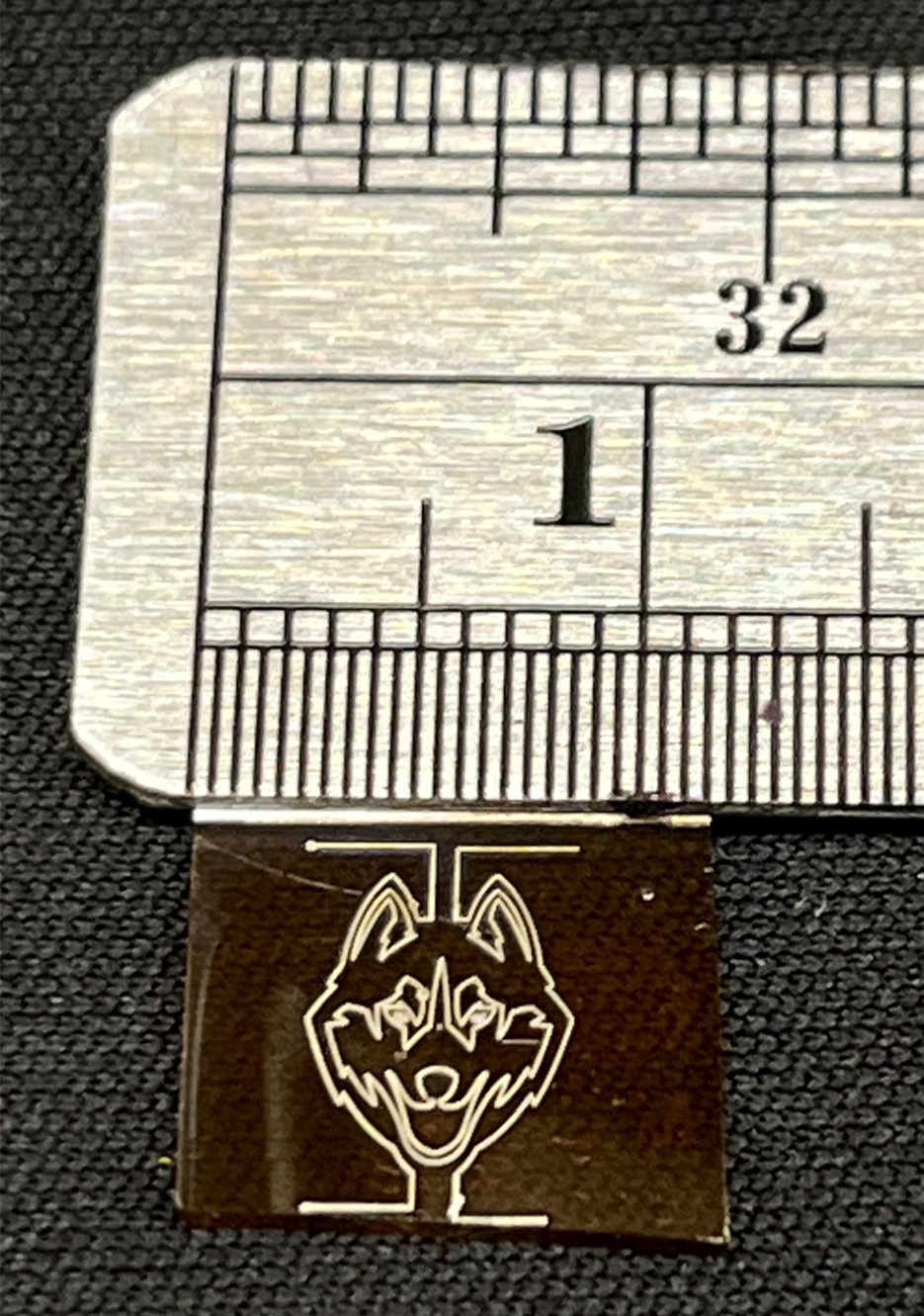 Small flexible circuit featuring a UConn Husky logo next to a measurement ruler.