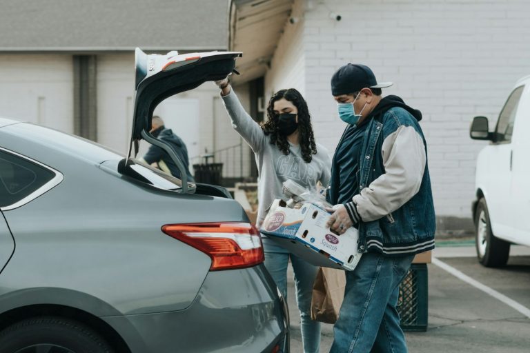 Man and woman in masks loading food into a car