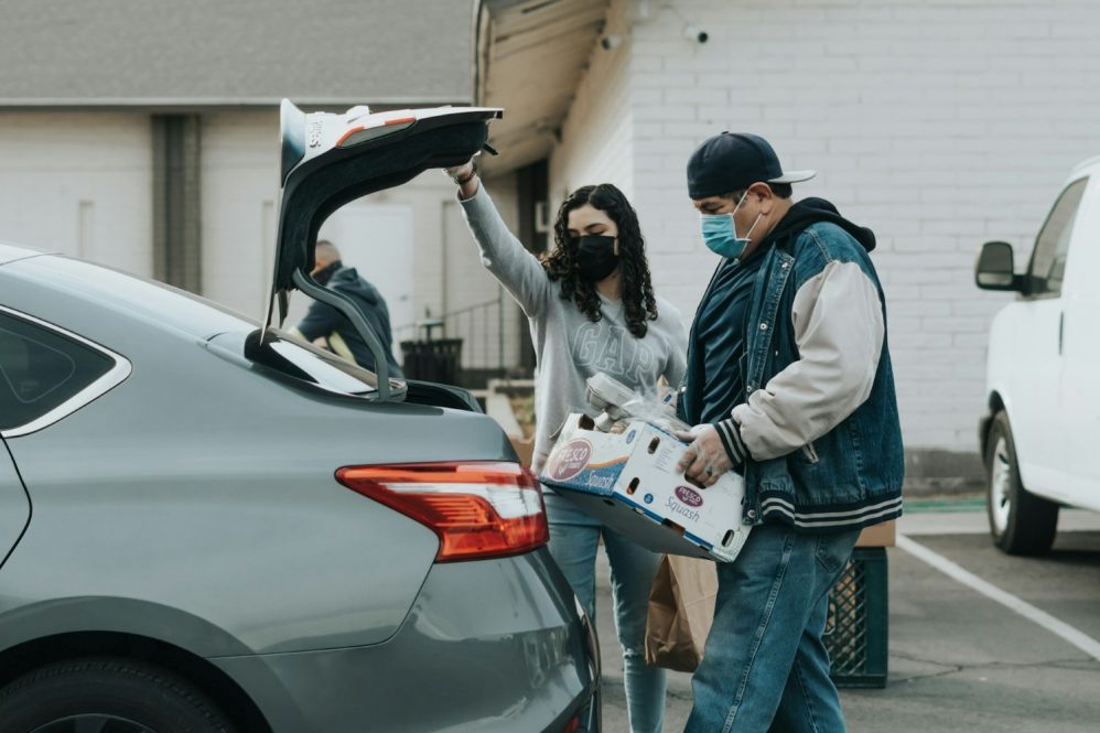 Man and woman in masks loading food into a car