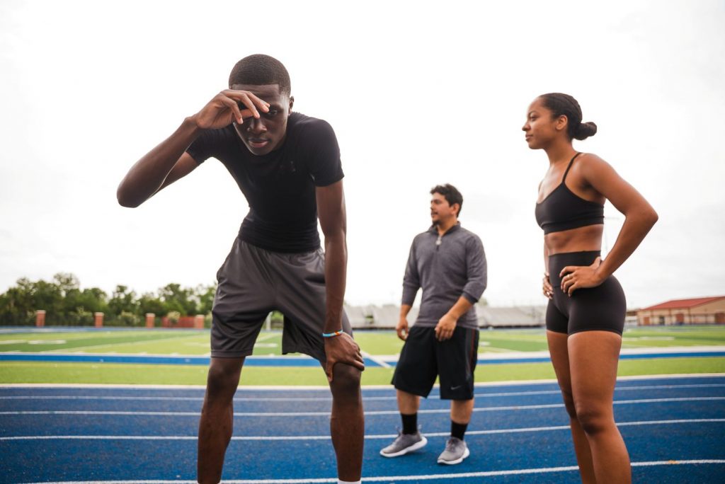 Men and women on a track, sweating