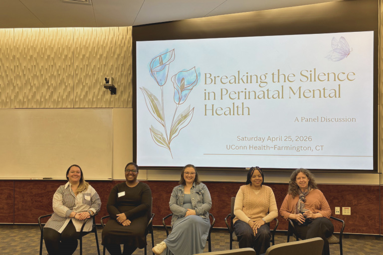 5 women sitting in a row in front of a screen that says Breaking the silence in Perinatal Mental Health