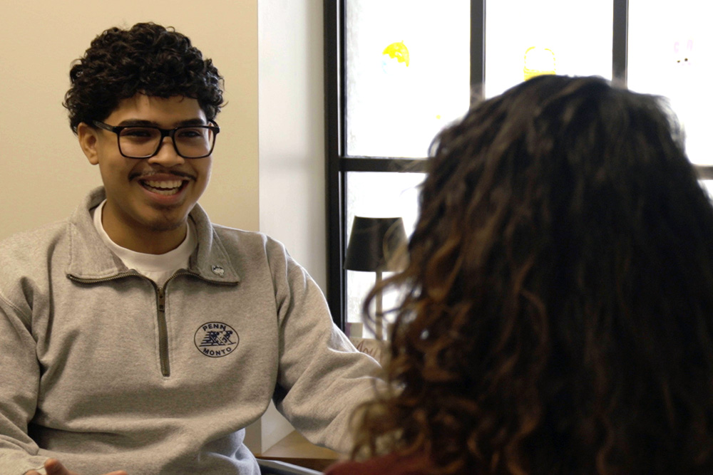 Man smiling while facing another person who you only see back of their head.