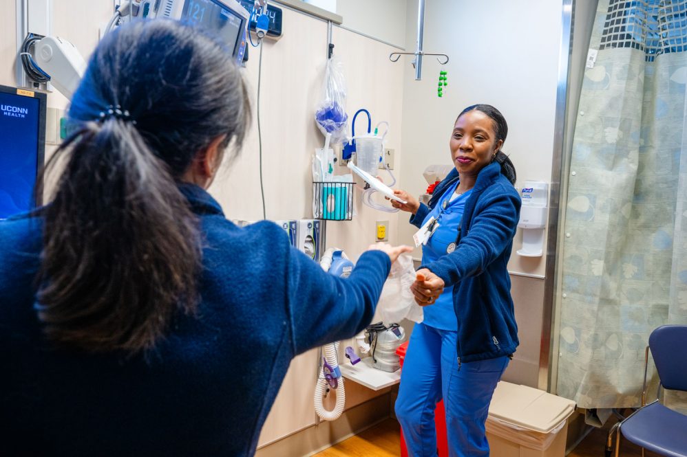 nurse handing a supply to a co-worker in postoperative setting