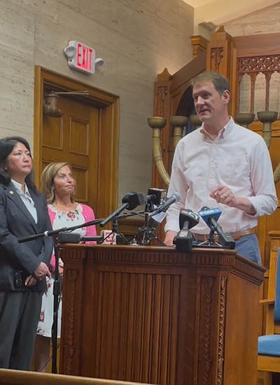 Ken Barone speaks at a podium during a press conference.
