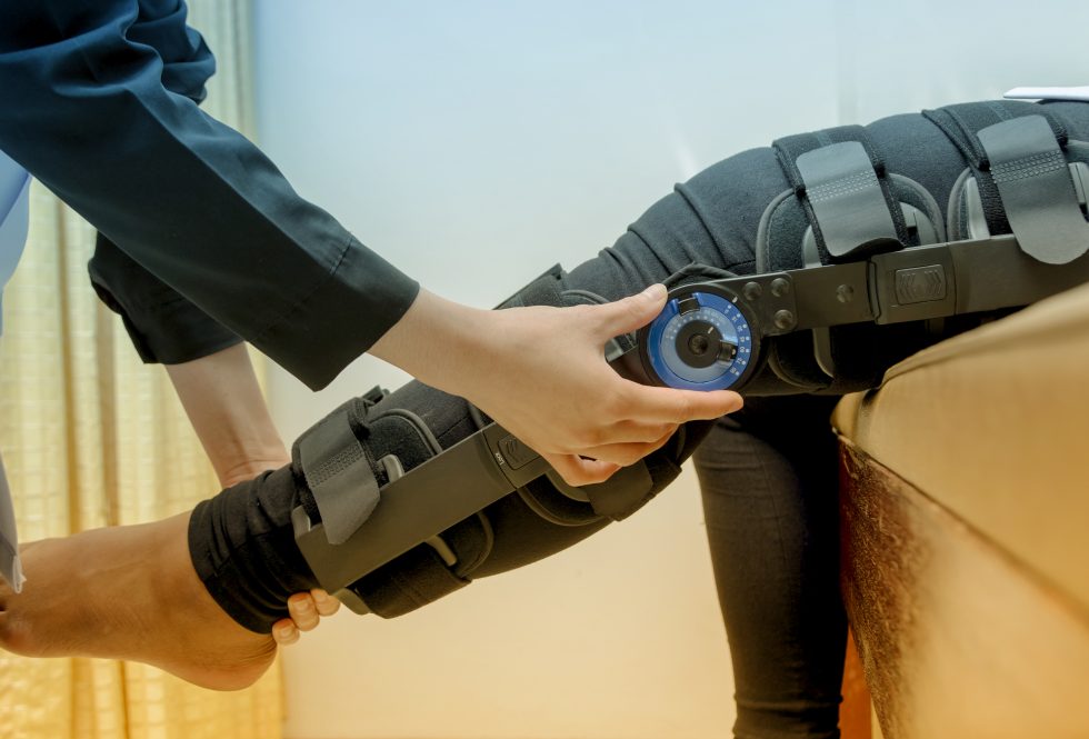 A physiotherapist adjusts a knee brace on a patient 's leg,