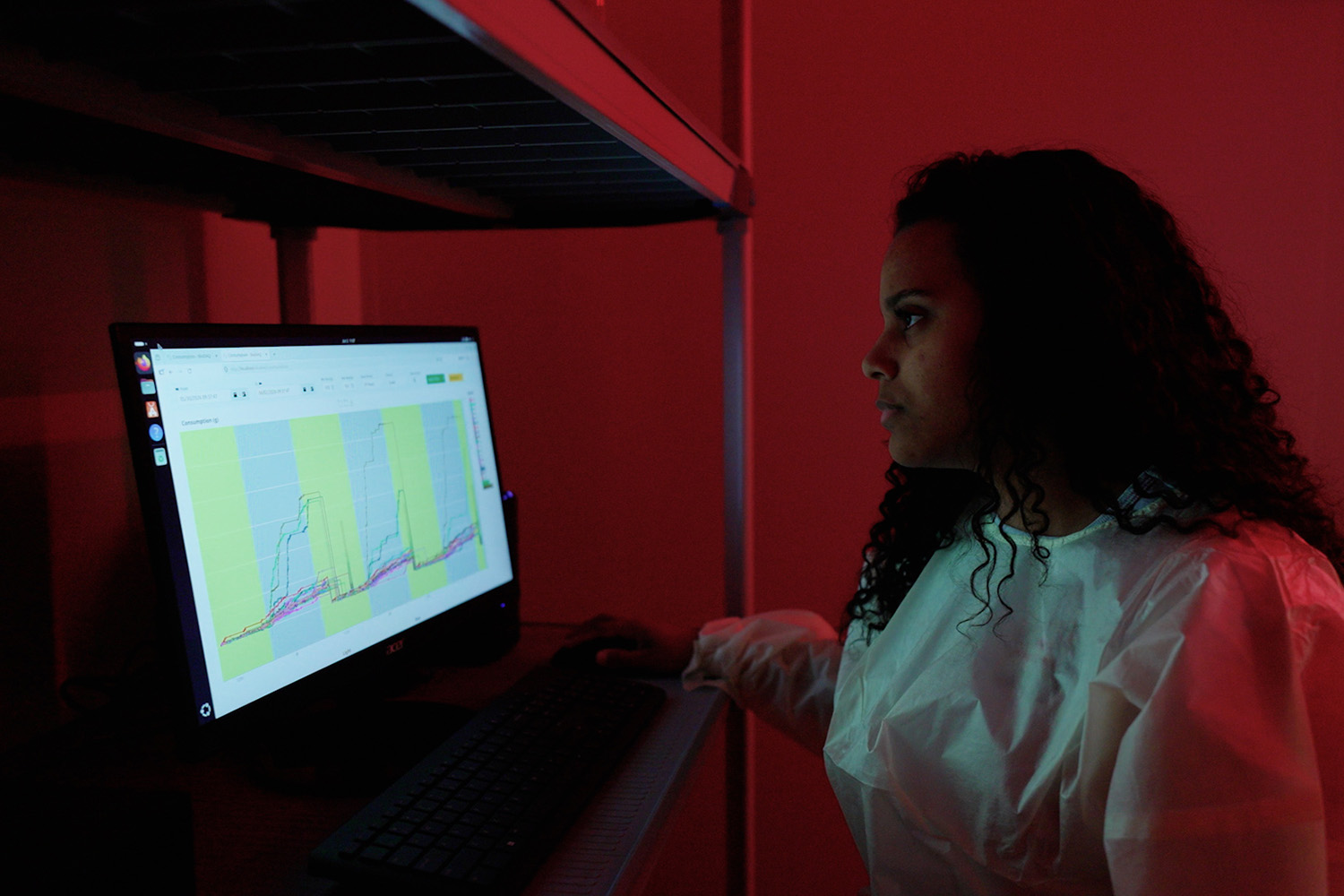A woman staring at a screen with data on it with red light in the background