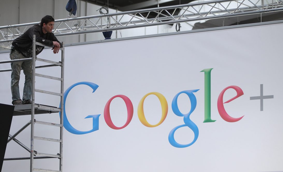 A man stands on a scaffold in front of a huge screen that reads "Google+".