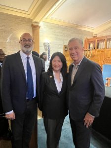 Three people wearing suits stand in a line.