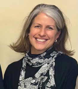 A woman in a black shirt with a black and white scarf wrapped around her neck.