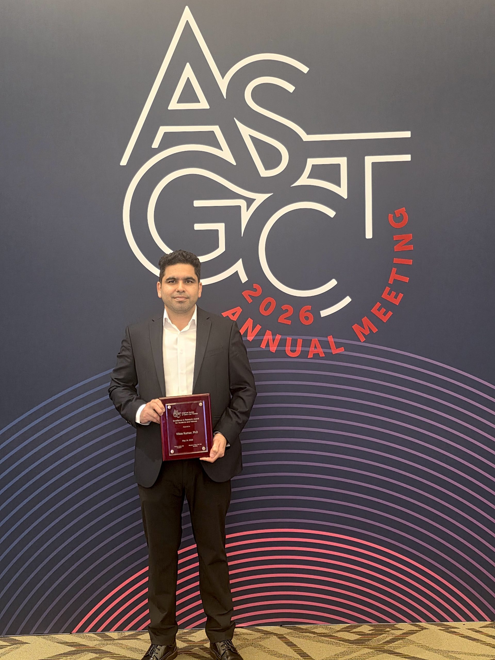 Man with brown hair holding his award at an annual conference