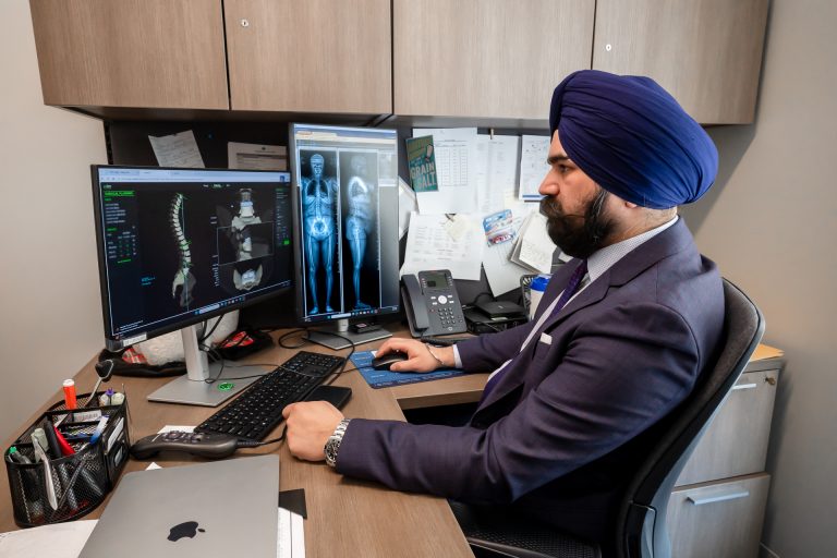 Spine surgeon Hardeep Singh sitting in his office reviewing digital images for an upcoming spinal surgery. (Tina Encarnacion/UConn Health photo)