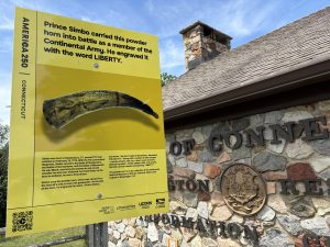 A yellow historical sign outside a highway rest stop.