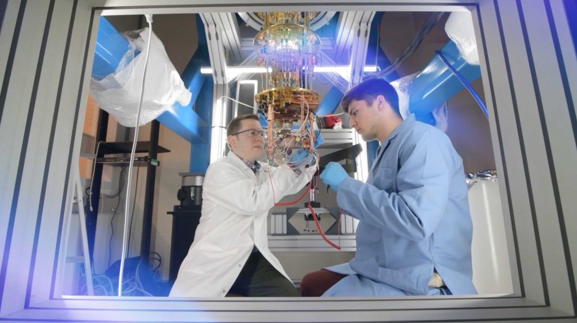 Two researchers in lab clothes work on a project.