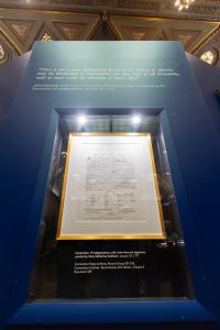 A copy of the Declaration of Independence on displya in a blue glass case