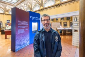 A man stands in front of a display that reads "Connecticut's Revolution"