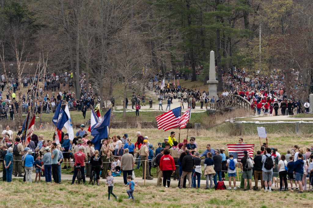 People march in a parade carrying American flags.