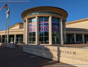 Posters celebrating "America 250" hang inside windows of a stone building marked as the Abraham Lincoln Presidential Museum.