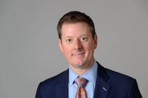 headshot of a man in a blue blazer
