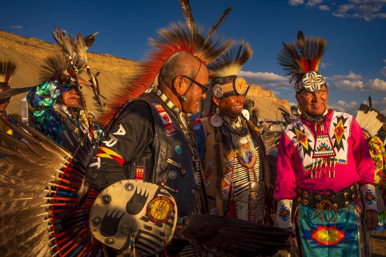 Three Native American men in regalia smiling