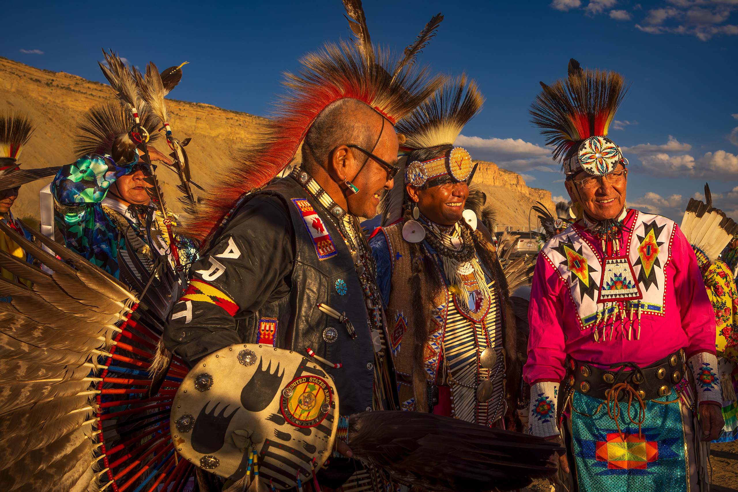 Three Native American men in regalia smiling