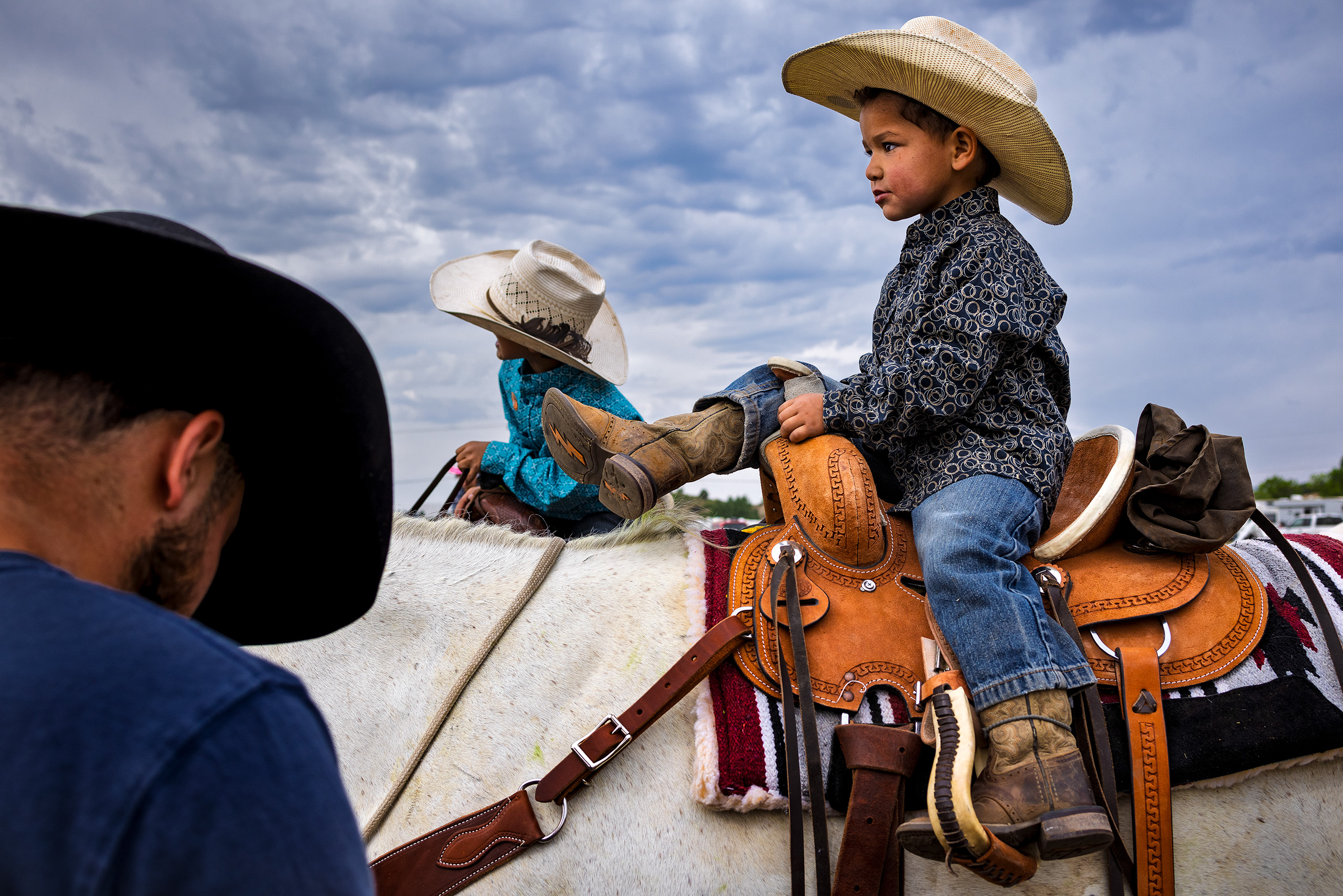 A young boy in a cowboy hat sits atop a horse