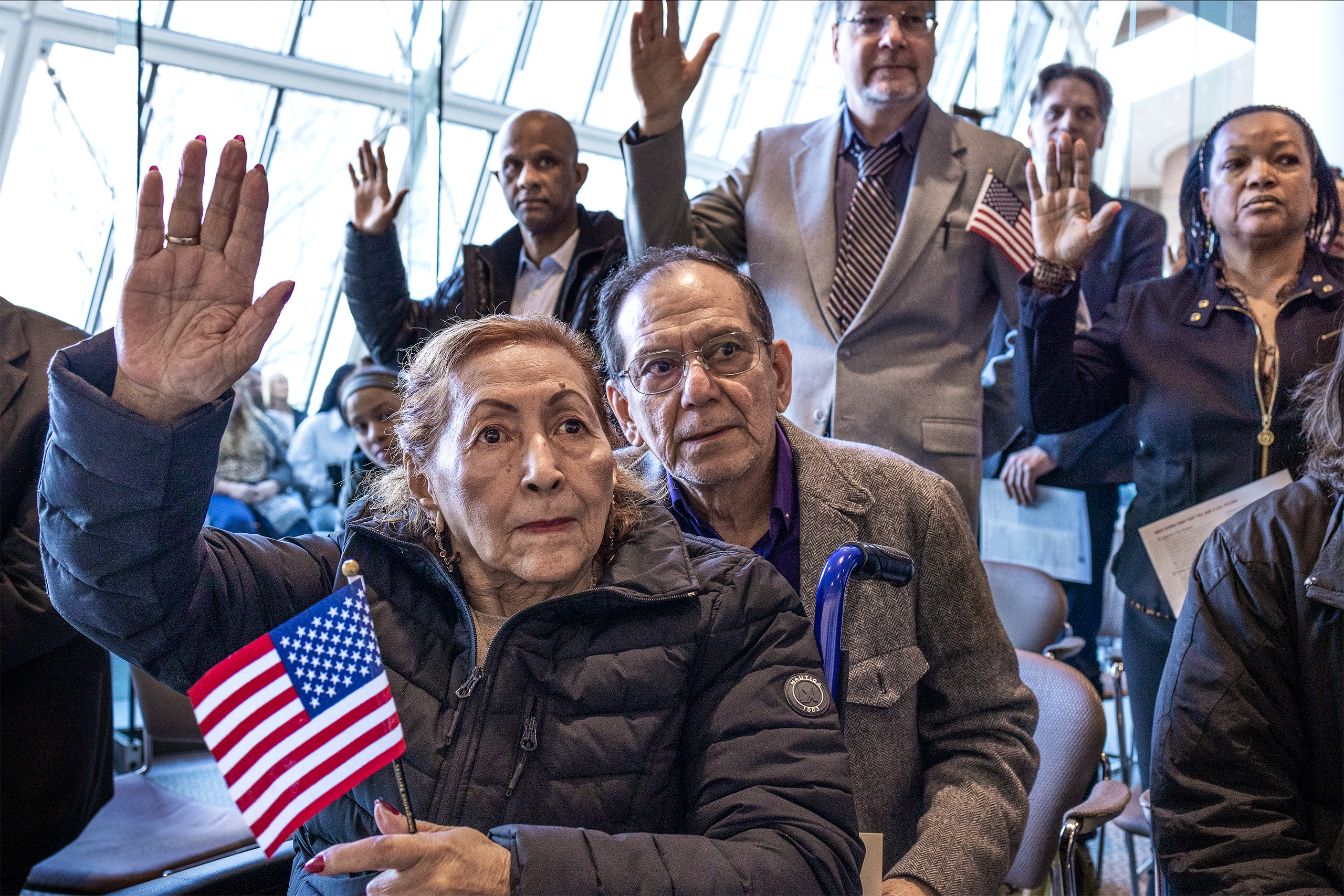 People participating in a naturalization ceremony with a woman holding an American flag