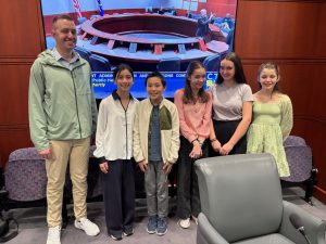 A male and five students pose in front of the legislative session