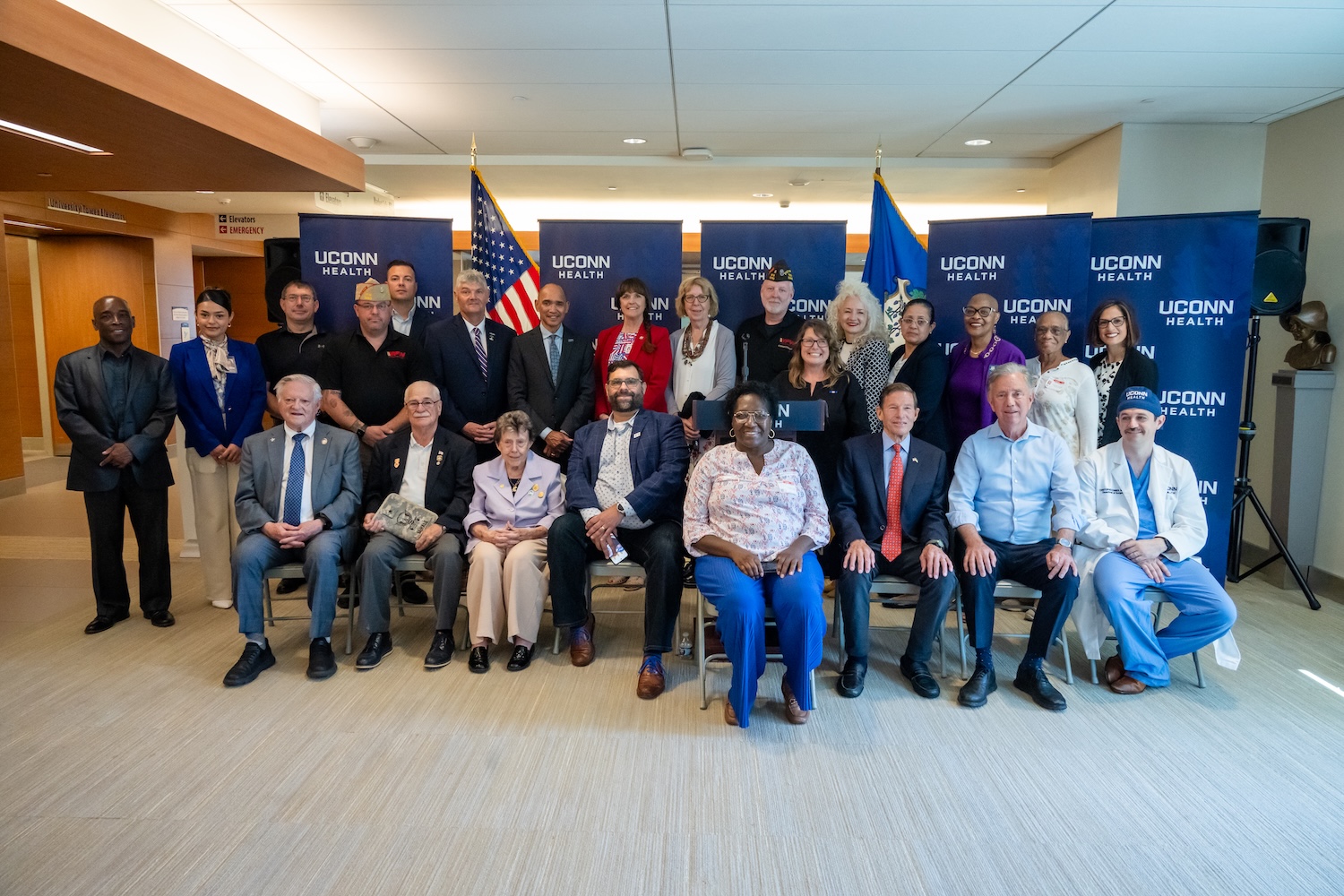 a large group of people posing for a photo in front of American and CT flags