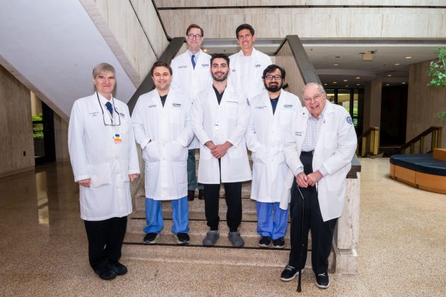 Group portrait indoors seven men in white coats