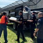 Corrections officers work with an inmate to unload a truck on planting day.