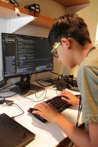 A young male student coding a robotic car
