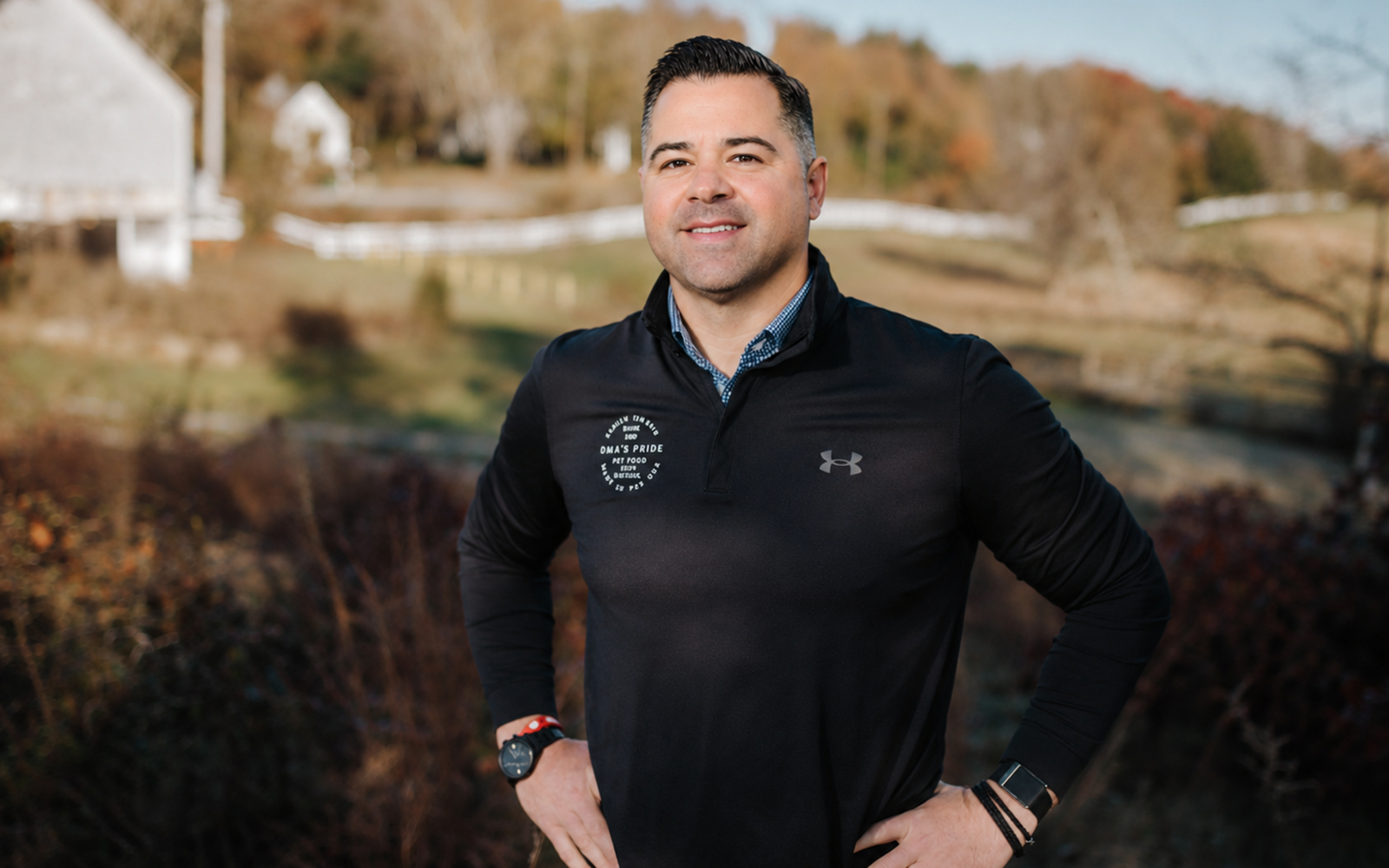 A man stands with a farm in the background.