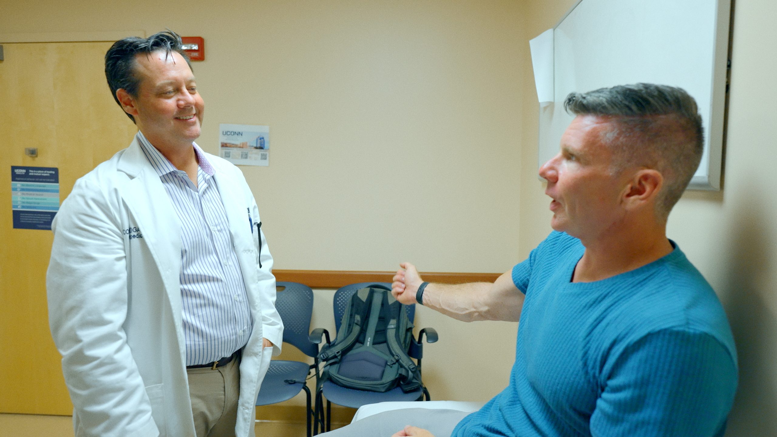Rory McGloin and UConn Health orthopedic surgeon Cory Edgar during an exam. Dr. Edgar repaired McGloin's bicep tendon after he tore it during a Gaelic football game last year. (Ethan Giorgetti/UConn Health)