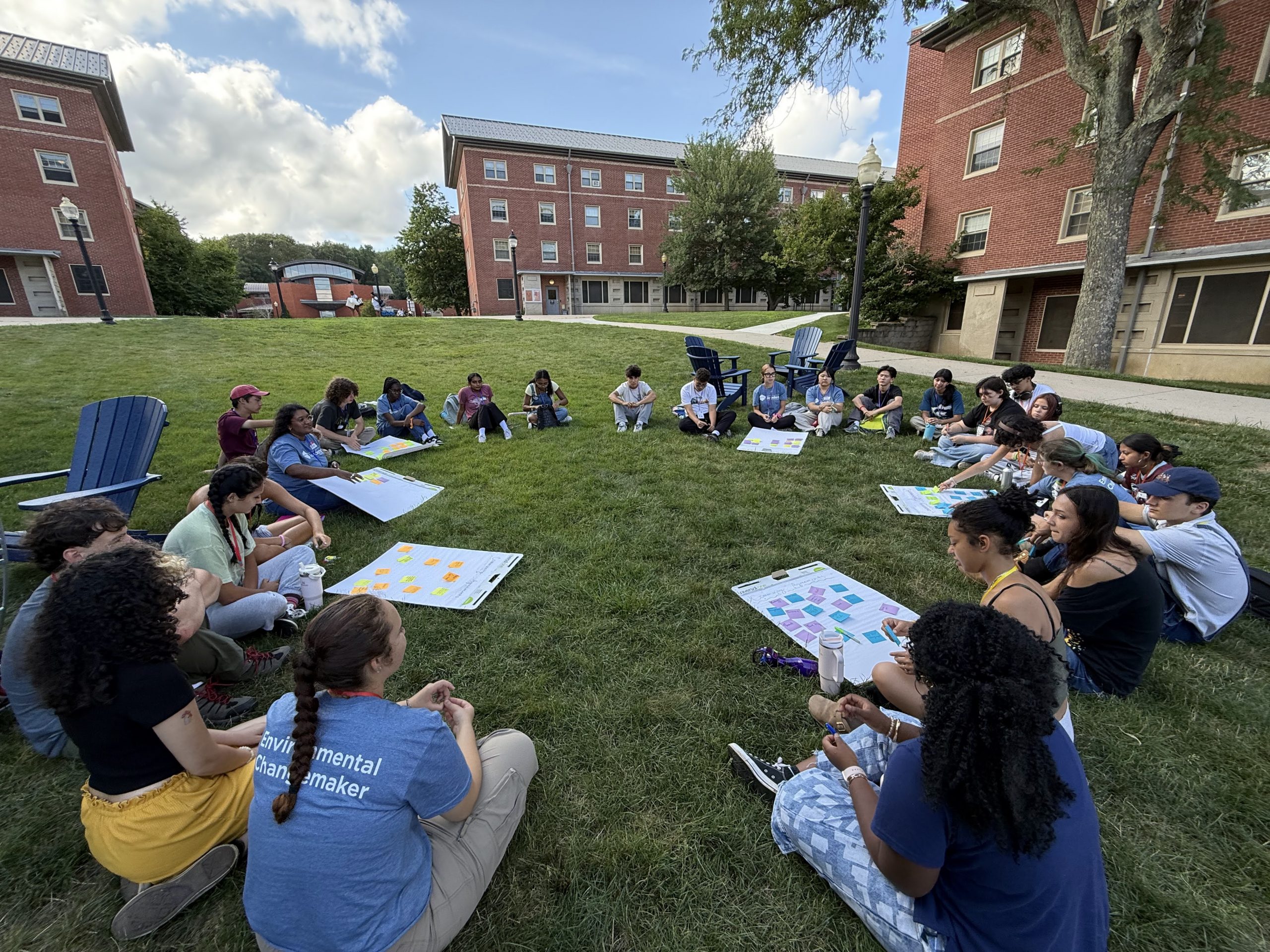 A group of students sitting in the grass outside UConn buildings