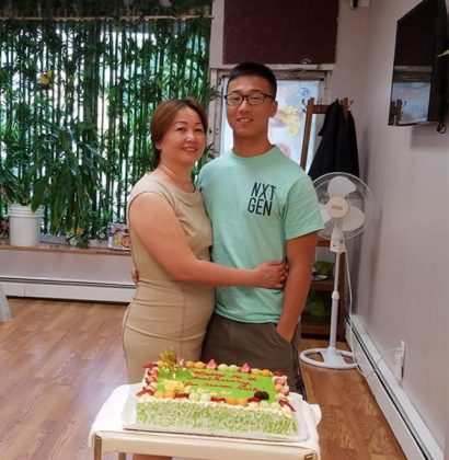 A mom and son standing together behind a sheet cake