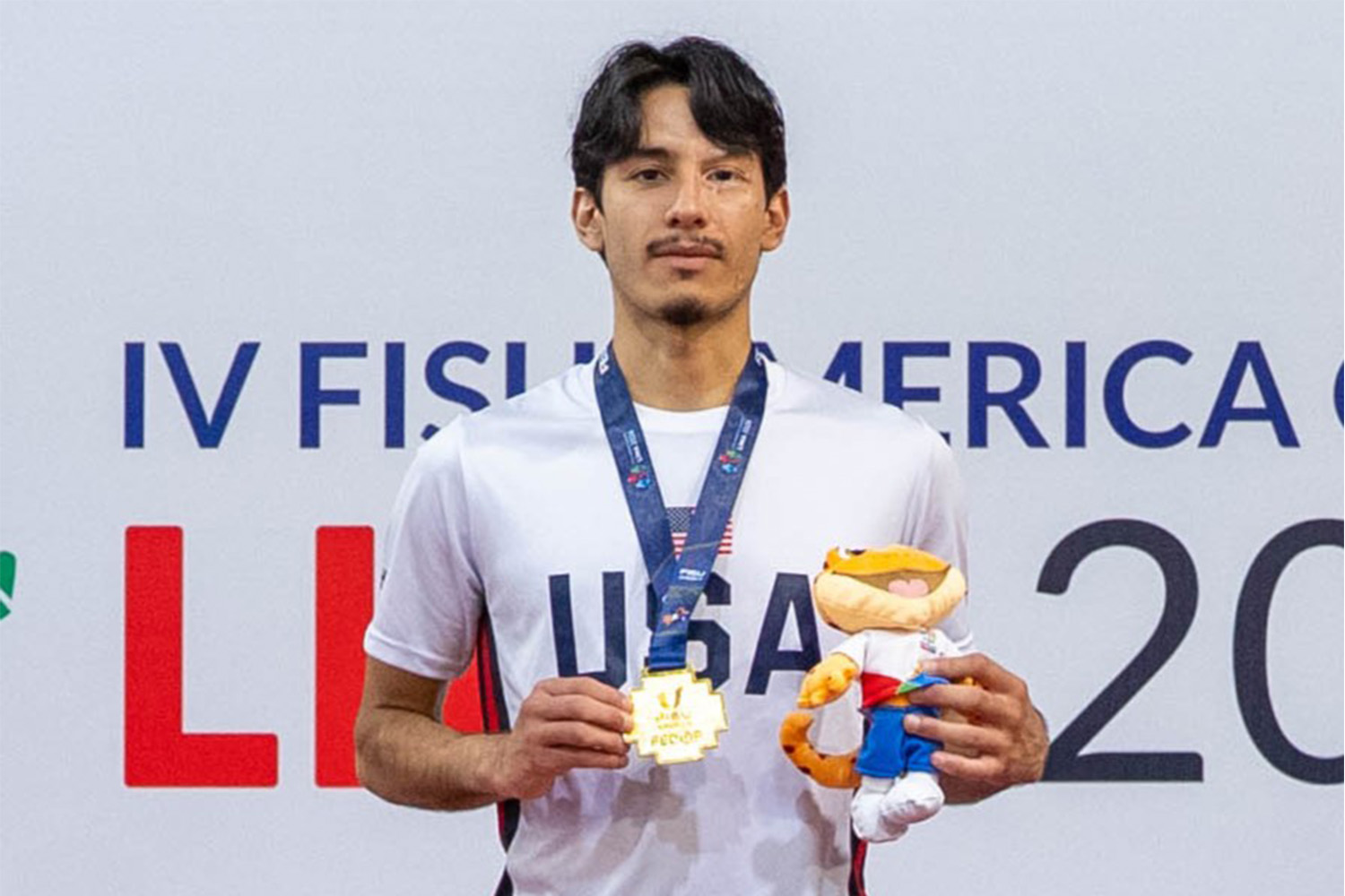A male student poses with a medal with a USA shirt on