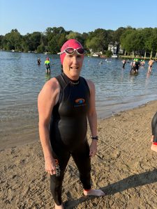 Woman in a wet suit standing in front of lake