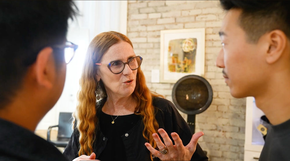Two men talking to a woman with glasses in salon
