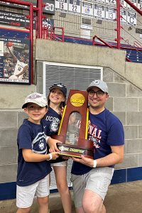 A man and his children pose with a basketball trophy in Gampel Pavilion in Storrs, CT. 